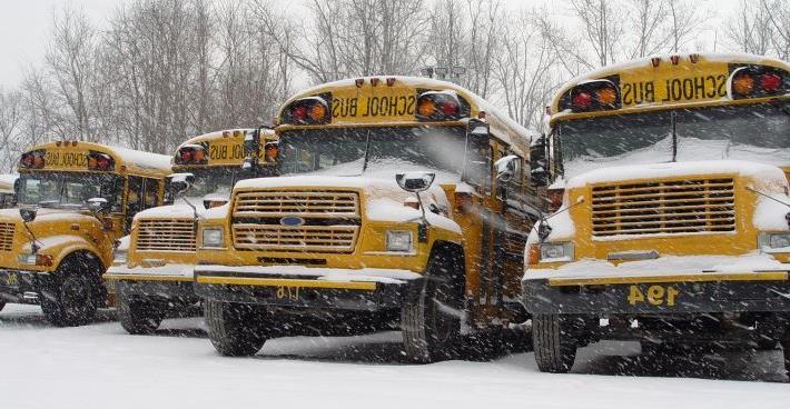 4 parked school buses with snow falling